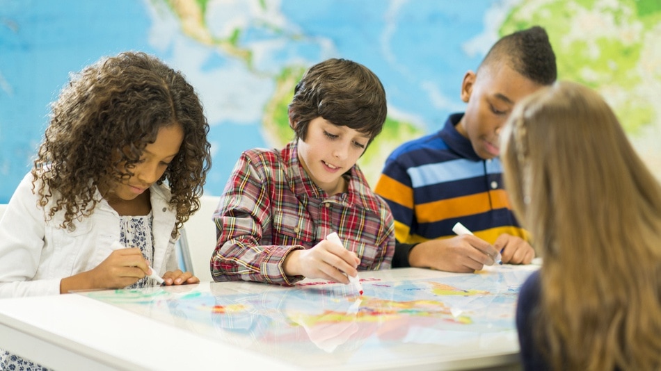 Niños de secundaria coloreando sobre un mapa