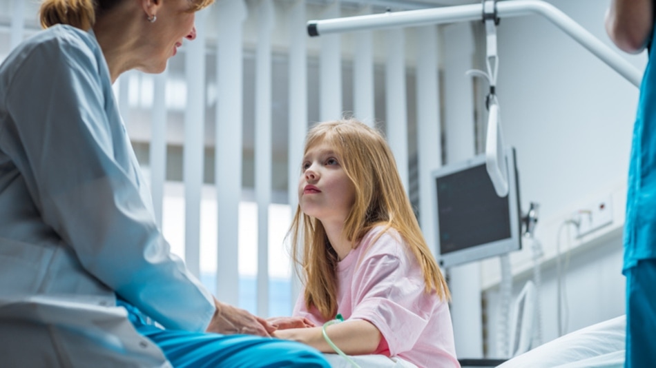 Niña en una cama de hospital hablando con la doctora 