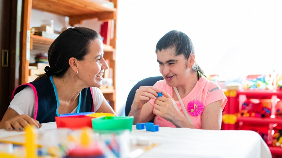 Profesora ayudando a una niña con discapacidad