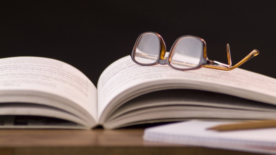 Análisis literario, gafas apoyadas en un libro abierto