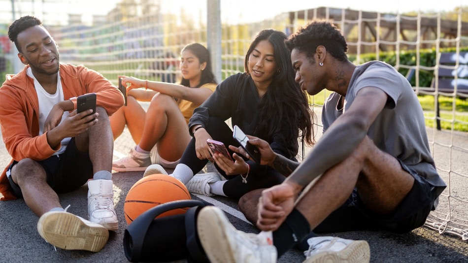 Aficionados al deporte del baloncesto mirando las redes sociales en un descanso