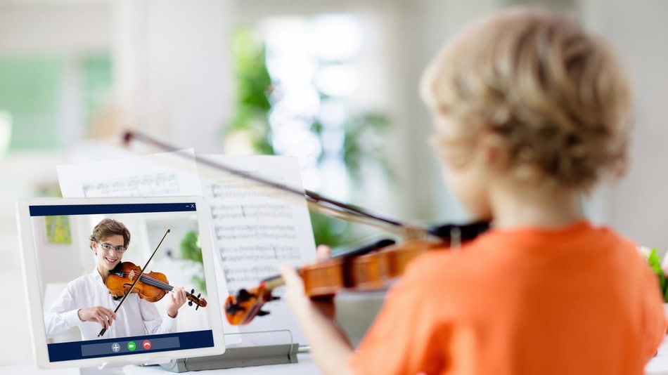 Pedagogo musical dando clase de violín online a un niño