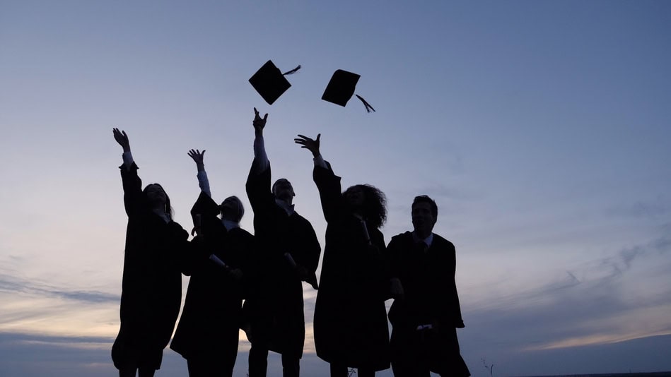 Grupo de estudiantes graduados lanzando los birretes al aire