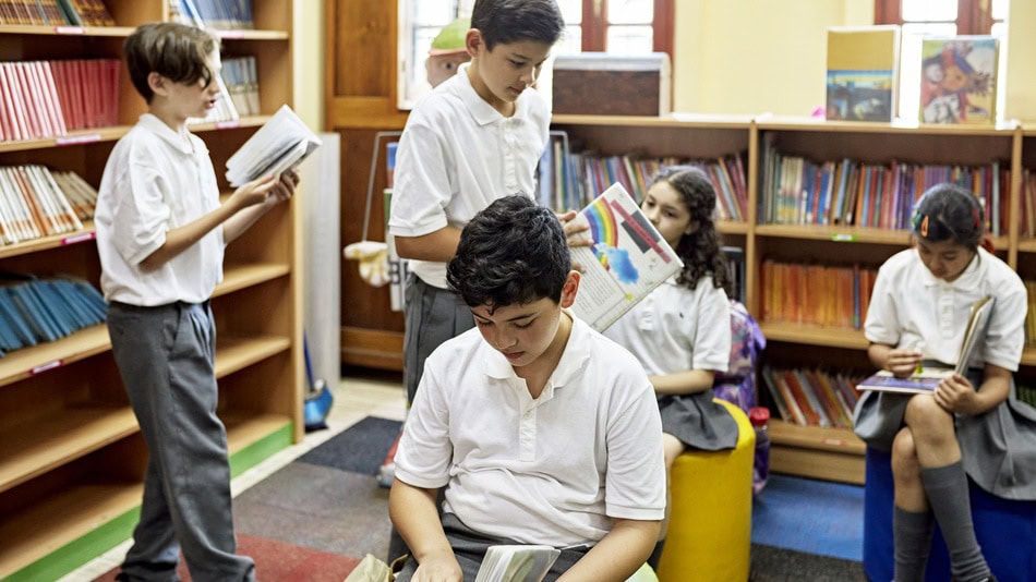 La didáctica de la lengua se centra en el proceso de enseñar, niños de primaria en el aula leyendo