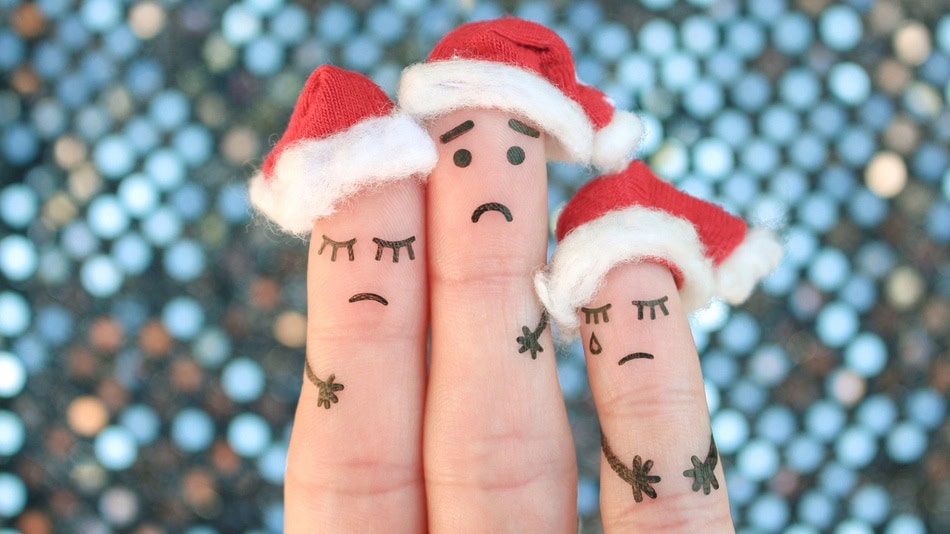 3 dedos juntos con gorro navideño y rostro triste con depresión navideña