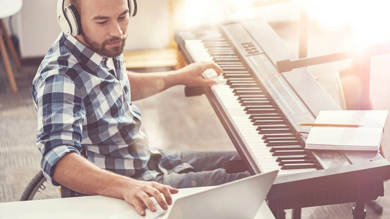 Componer en tiempos de COVID. Chico joven compone al piano. 