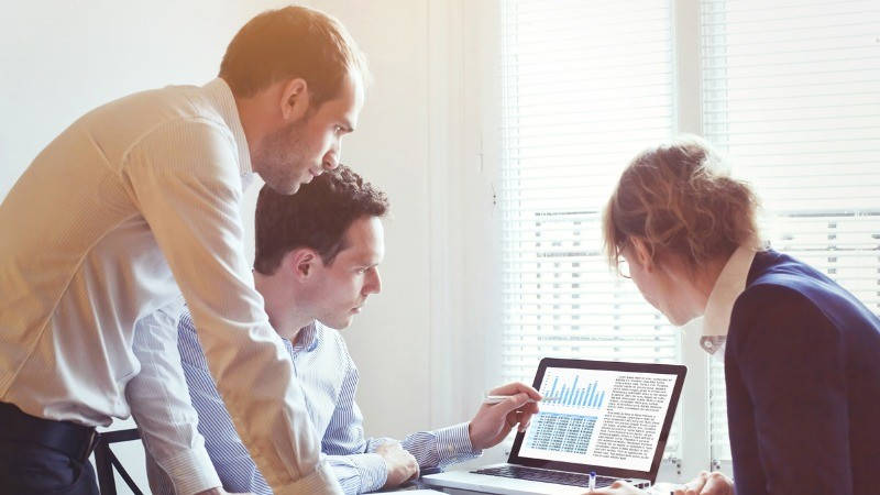 Big Data. Dos hombres y una mujer mirando el ordenador con gráficos.