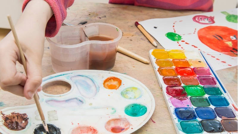 Educación, plástica infantil; un niño pintado con acuarelas