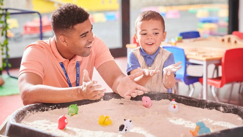 Educación, atención temprana; un profesor juega con un niño con arena