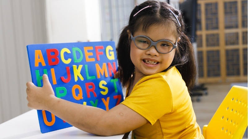 Niña con Síndrome de Down jugando con un puzzle del alfabeto