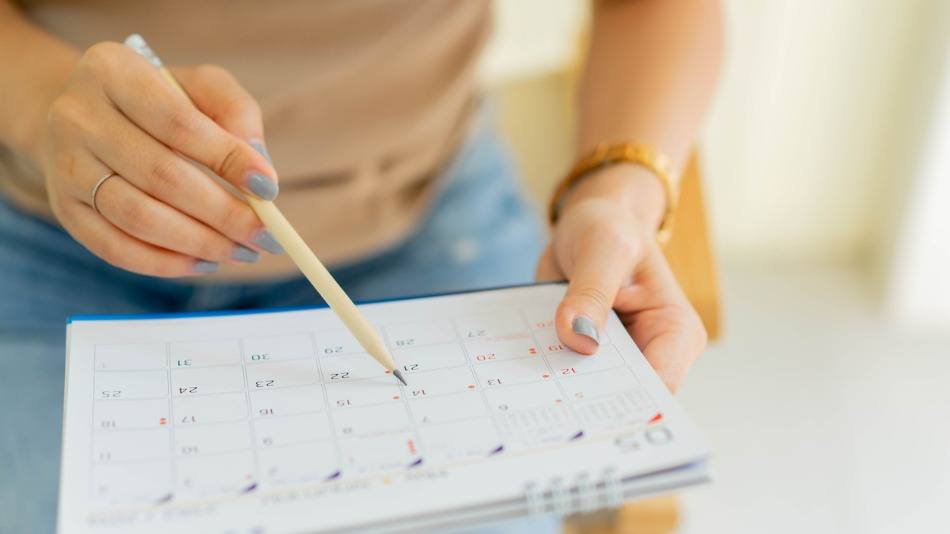 Calendario editorial; una mujer apuntando en un calendario con un lápiz 