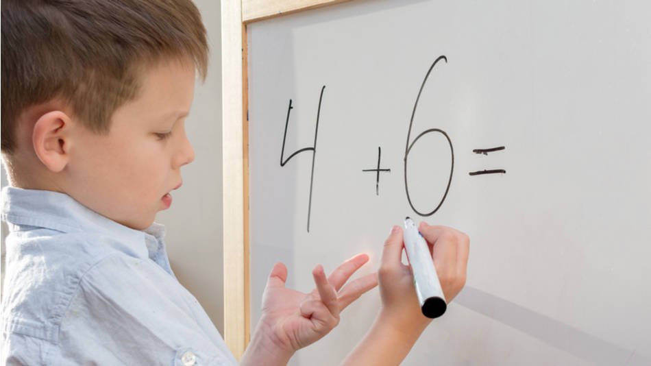 Método ABN para enseñar matemática; un niño sumando con sus dedos un problema en pizarra