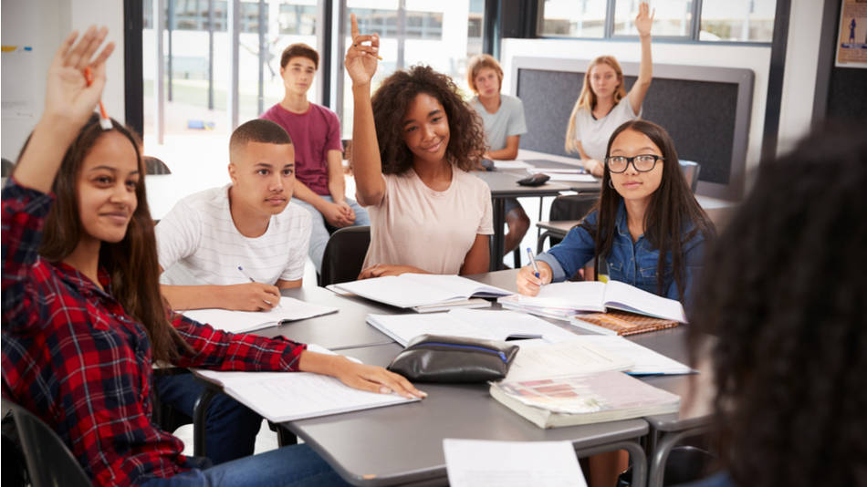 Educación Inclusiva; Actividades para trabajar la interculturalidad en secundaria; un grupo de adolescentes en el aula con manos levantadas y sonrientes